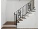 Close-up view of a staircase with hardwood steps and black ornate railings at 2725 Glendale Ne Dr, Conyers, GA 30013