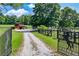 Scenic property featuring a gated entry, barn, and house, nestled amidst lush greenery and a gravel driveway at 1780 Penn Camp Road, Douglasville, GA 30134