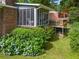 Brick home featuring a screened porch, wooden deck, and lush landscaping with blue hydrangea bushes at 8415 Ridge Rd, Fairburn, GA 30213