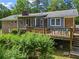 Brick home boasts a screened porch and wooden deck with seating, complemented by vibrant green landscaping at 8415 Ridge Rd, Fairburn, GA 30213