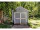 Exterior view of a gray storage shed with double doors in a wooded backyard at 1268 Thomas Rd, Decatur, GA 30030