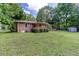 Back exterior features a brick facade, covered patio, mature landscaping, and a well-maintained lawn at 4545 Gaydon Rd, Powder Springs, GA 30127