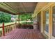 Outdoor view of a covered back porch with a stained wood deck, brick siding, and a serene yard view at 4545 Gaydon Rd, Powder Springs, GA 30127