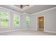 Sunlit bedroom with tray ceilings featuring three windows and an attached bathroom at 2021 Towneship Trl, Roswell, GA 30075