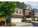 Two-story brick townhome featuring a two-car garage, well-maintained landscaping, and charming architectural details at 2021 Towneship Trl, Roswell, GA 30075