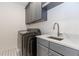 Well-lit laundry room features gray cabinets, modern washer and dryer set, and stylish tile flooring at 338 Sugarview Rd, Sugar Hill, GA 30518
