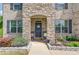 Inviting front porch with stone accents, a black door with a wreath, and decorative plants at 4931 Pauls Pointe, Sugar Hill, GA 30518