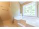 Bright bathroom featuring a soaking tub, shower, a large window and neutral color scheme at 5425 Windswept Trce, Sugar Hill, GA 30518