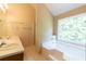 Bright bathroom featuring double sinks, soaking tub, shower, and a large window at 5425 Windswept Trce, Sugar Hill, GA 30518