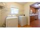 Bright laundry room featuring a washing machine and dryer, with wire racks for storage, and hardwood flooring at 5425 Windswept Trce, Sugar Hill, GA 30518