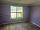 Bright bedroom with violet painted walls features a window, light fixture and shelving at 621 Ridge Creek Dr, Clarkston, GA 30021