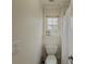 Neutral toned bathroom with a toilet near a window and a white shower curtain at 1320 Kildare Ct, Snellville, GA 30078