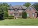 Two-story red brick home featuring a well-manicured lawn and lush, mature landscaping at 1320 Kildare Ct, Snellville, GA 30078