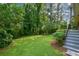 Green backyard with stairs leading to the house surrounded by lush trees at 1376 Woodbine St, Marietta, GA 30062
