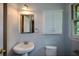 Clean bathroom featuring a pedestal sink, vanity mirror, toilet and cabinet for storage at 1376 Woodbine St, Marietta, GA 30062
