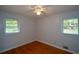 Minimalist bedroom with two bright windows, light walls, hardwood floors, and a ceiling fan at 1376 Woodbine St, Marietta, GA 30062
