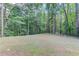 Level backyard area surrounded by mature trees, offering privacy and space for outdoor activities at 5345 Pilgrim Point Rd, Cumming, GA 30041