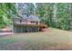 Rear exterior view featuring a tiered deck, lush backyard, and home with light green siding at 5345 Pilgrim Point Rd, Cumming, GA 30041