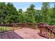 Open, stained wood back deck with wood railing and lush green trees in the background at 140 Melrose Creek Dr, Stockbridge, GA 30281