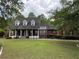 Traditional red brick home featuring dormer windows, a large covered porch, and well-manicured landscaping at 349 Bald Rock Rd, Oxford, GA 30054