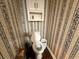 A traditional half bathroom with a toilet, floral wallpaper, and patterned floors at 349 Bald Rock Rd, Oxford, GA 30054