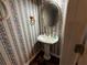 A quaint powder room with a pedestal sink, floral wallpaper, and decorative mirror at 349 Bald Rock Rd, Oxford, GA 30054