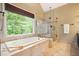 Bathroom featuring a soaking tub, glass shower, and a large window with natural light at 1206 Mountainside Nw Trce, Kennesaw, GA 30152