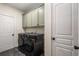 Well-organized laundry room with washer, dryer, upper cabinets, and neutral decor at 1607 Boulder Walk Se Dr, Atlanta, GA 30316