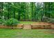 A backyard with lush greenery and wood retaining wall and stair feature at 8895 Club River Dr, Roswell, GA 30076