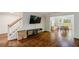 Bright living room featuring hardwood floors, an entertainment center, and access to the dining area at 8895 Club River Dr, Roswell, GA 30076