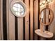 Unique powder room featuring a round window, custom wallpaper, and a pedestal sink at 136 Parkstone Way, Marietta, GA 30066