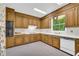 Functional kitchen featuring wooden cabinets, white appliances, and a window with a wooded view at 740 Skyline Dr, Covington, GA 30014