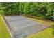 Overhead shot of a fenced tennis court surrounded by mature trees and manicured lawns at 740 Skyline Dr, Covington, GA 30014