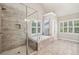 Bright bathroom featuring a glass-enclosed shower and soaking tub with shuttered windows at 2585 Drew Valley Ne Rd, Brookhaven, GA 30319