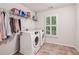 Well-lit laundry room with white front-loading washer and dryer and storage shelf at 2585 Drew Valley Ne Rd, Brookhaven, GA 30319
