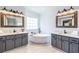 White bathroom featuring double vanity, mirrors with wooden frames, and freestanding tub at 3845 Glen Ian Dr, Loganville, GA 30052