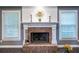 Close up of the fireplace with white mantle, brick surround, and decorative sunburst mirror at 3845 Glen Ian Dr, Loganville, GA 30052