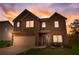 Two-story brick home featuring a two-car garage, blue shutters, and a manicured front lawn at sunset at 1173 Gaines St, Jonesboro, GA 30238