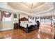 Spacious main bedroom with hardwood floors, a chandelier, tray ceilings and large windows at 3332 Heathchase Ln, Suwanee, GA 30024