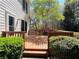 Home's wooden deck features a stained wood, wood railing, and green shrubs under a shady blue sky at 415 Wood Trace Ct, Alpharetta, GA 30022