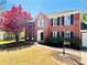 Traditional brick two-story home with black shutters, manicured lawn, and a red maple tree at 415 Wood Trace Ct, Alpharetta, GA 30022