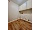 Well-lit laundry room with laminate wood flooring and convenient overhead storage at 415 Wood Trace Ct, Alpharetta, GA 30022