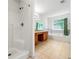 Bright bathroom features double sinks with wooden cabinets, bathtub, stand up shower, and large window with green curtains at 85 Old Gettysburg Way, Dallas, GA 30157