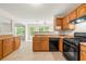 Kitchen featuring light wood cabinets, black appliances, and tile floors at 85 Old Gettysburg Way, Dallas, GA 30157
