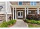 Welcoming front porch featuring stone accents, white columns, and a pathway with yellow flowers at 3415 Kenyon Creek Nw Dr, Kennesaw, GA 30152