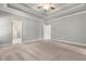 Spacious main bedroom with carpet, neutral colors, and tray ceiling leading to a bathroom at 3415 Kenyon Creek Nw Dr, Kennesaw, GA 30152