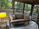 Inviting screened-in porch with a cozy couch, end table, and views of the serene, wooded backyard at 3474 Leaf Land Ct, Duluth, GA 30097