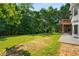 Spacious backyard with a grassy lawn, mature trees, and a stone patio at 7025 Bavarian Wood Pl, Buford, GA 30518