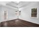 Bright bedroom featuring tray ceiling, hardwood floors, and natural light from two large windows at 7025 Bavarian Wood Pl, Buford, GA 30518