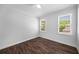Bedroom featuring hardwood floors, white walls and trim, and natural light from two large windows at 7025 Bavarian Wood Pl, Buford, GA 30518